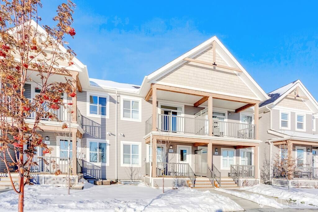 A multi-story residential building with a central balcony, multiple windows, and a snow-covered ground.