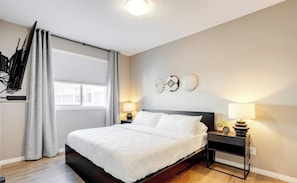 Un dormitorio moderno con una cama grande, lámparas de noche y decoración mural.