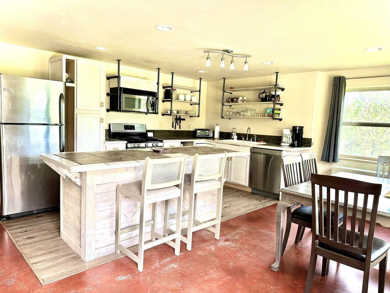 Une cuisine moderne dotée d’un îlot central, de tabourets de bar et d’une table à manger avec des chaises.