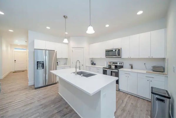 Enjoy cooking in this well-equipped kitchen with a central island, sink, and stainless steel appliances.