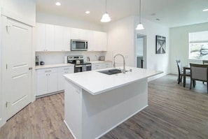 Enjoy cooking in this well-equipped kitchen with a central island, sink, and stove.