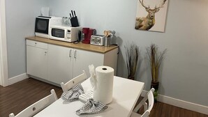 Uma cozinha compacta com micro-ondas, torradeira e um rolo de papel toalha no balcão.