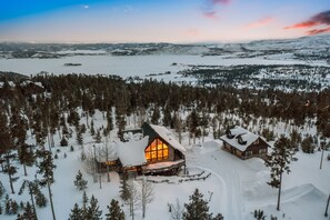 Une cabane entourée d’arbres couverts de neige et d’un lac.
