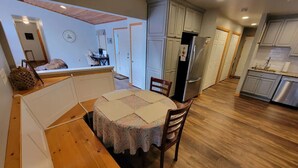 A compact kitchen with wooden cabinets, a refrigerator, and a dining area with a table and chairs. - Lakeside Waterfront: Private Dock - Near Lake Anna Winery (Bumpass)
