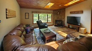 A cozy living room with a large leather sofa, a coffee table, and a flat-screen TV. - Lakeside Waterfront: Private Dock - Near Lake Anna Winery (Bumpass)
