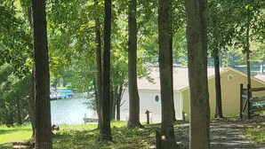 A wooded area with a lake, a dock, and a building with a circular window. - Lakeside Waterfront: Private Dock - Near Lake Anna Winery (Bumpass)