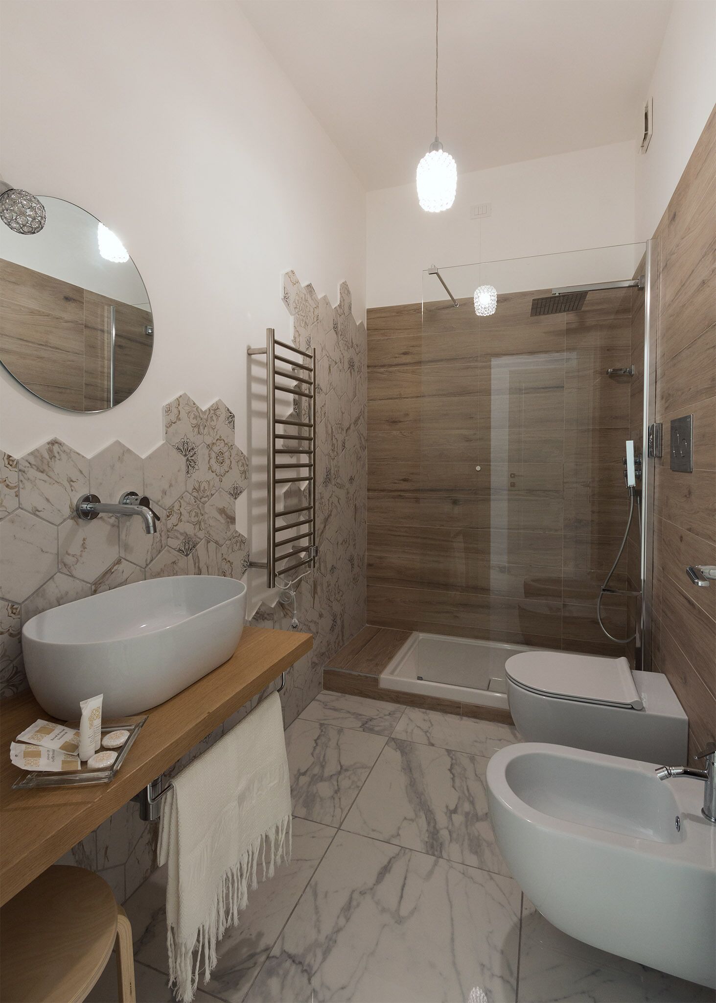 Een moderne badkamer met een groot ovaal wastafel, een badkuip, een douche met glazen wanden en een houten wastafelmeubel.