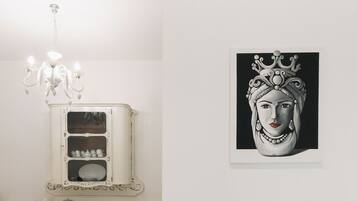 Un armario blanco con adornos y una obra de arte enmarcada en la pared.