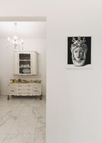 A white cabinet with decorative items and a framed artwork on the wall.