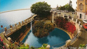 A waterfront area with a bridge, a large tree, and a building with a tower. - Calafatari B&B (Syracuse)