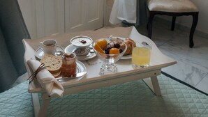A breakfast table with a variety of food items, a chair, and a window with curtains. - Calafatari B&B (Syracuse)