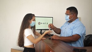 A reception desk with a monitor displaying the logo "natz". - NATZ HOTEL (Flores)