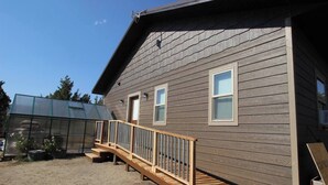 A two-story house with a wooden deck and a greenhouse.
