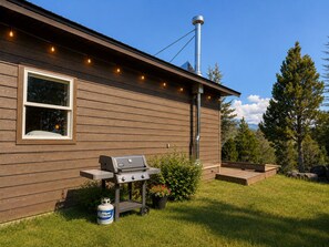 Une maison avec une façade en bois, une fenêtre, un barbecue et une bouteille de propane.