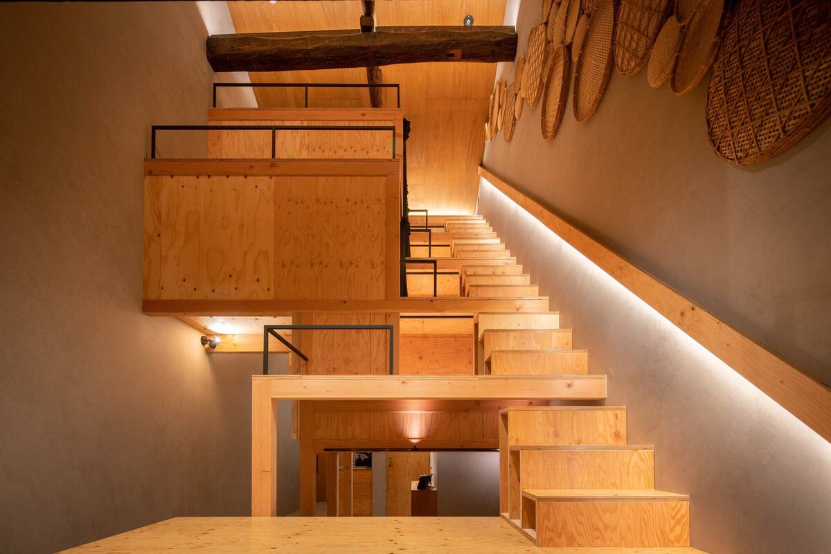 A wooden staircase with a modern design, featuring a wooden handrail and a series of steps leading upwards.