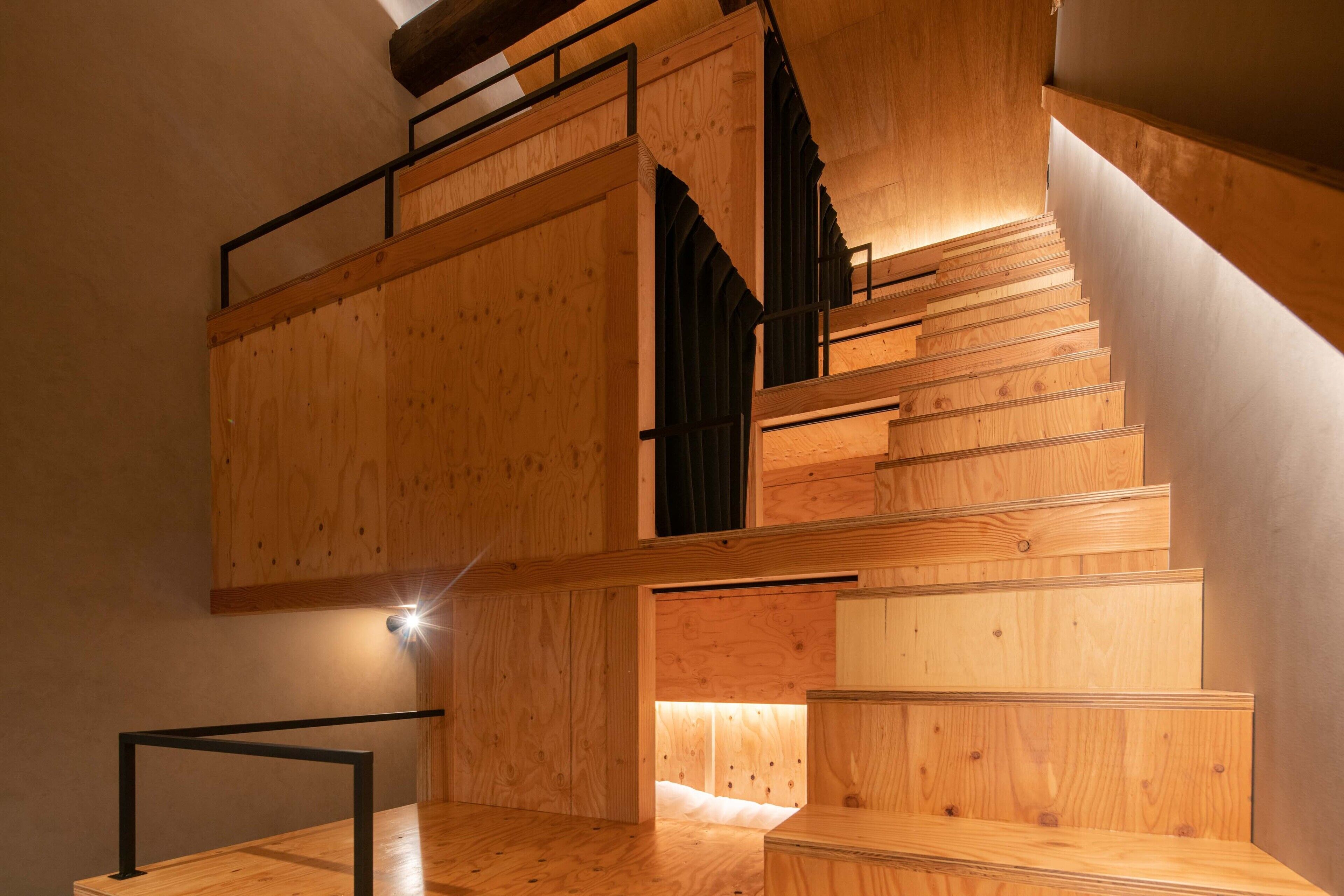 Eine Holztreppe mit Metallgeländer und einer Lichtquelle am oberen Ende.