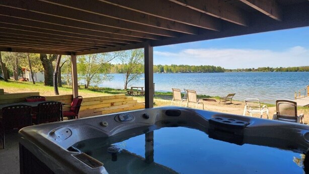 Jacuzzi sota una pèrgola de fusta amb vista a un llac i mobles de jardí.