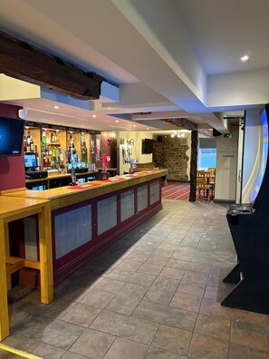 A bar area with a long counter, multiple taps, and a stone wall in the background. - St Ives (Neath)