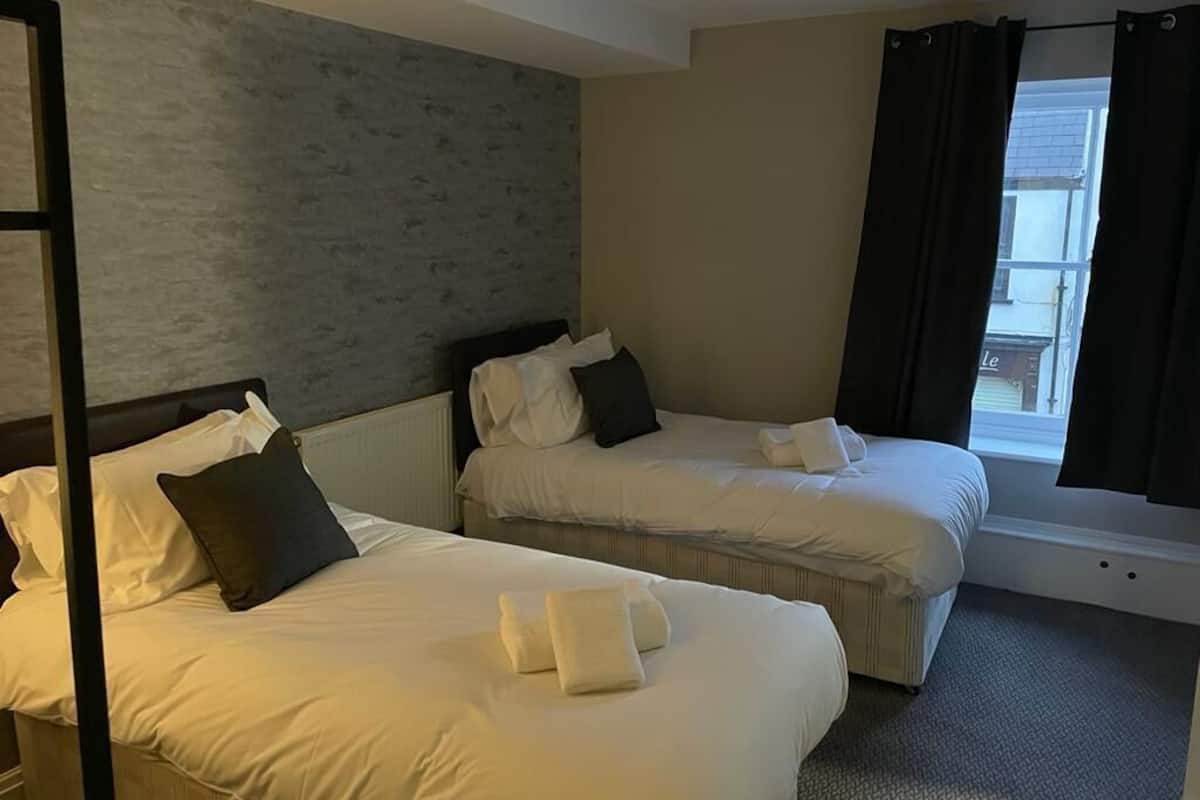 Quarto de hotel com duas camas, uma janela com cortinas e vista para o exterior.
