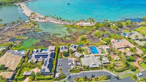 Eine Luftaufnahme eines Küstenresorts mit mehreren Gebäuden, einem Strand und klarem, blauem Wasser.