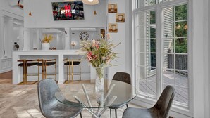 A modern kitchen with white cabinetry, a glass dining table, and a large window overlooking a deck. - Fancy Poconos Castle & Indoor MEGA 10+ Hot Tub (East Stroudsburg)