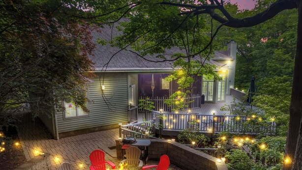 A patio with a fire pit, red chairs, and string lights. - Fancy Poconos Castle & Indoor MEGA 10+ Hot Tub (East Stroudsburg)