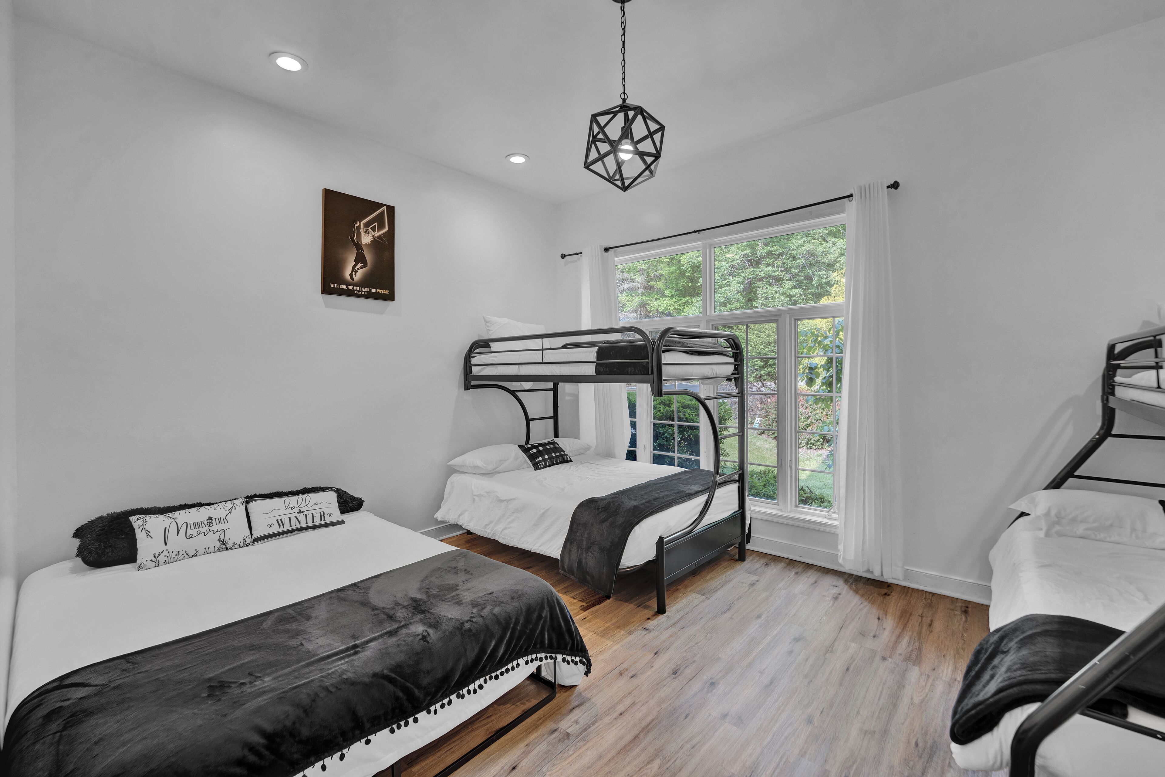 A modern bedroom with bunk beds, a large window, and a geometric light fixture.