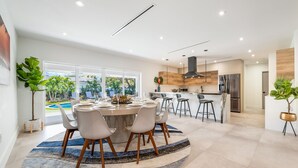 A modern kitchen with a central island, stainless steel appliances, and a view of a swimming pool. - Family getaway • Pool • BBQ • Golf • BB Court (Miami)