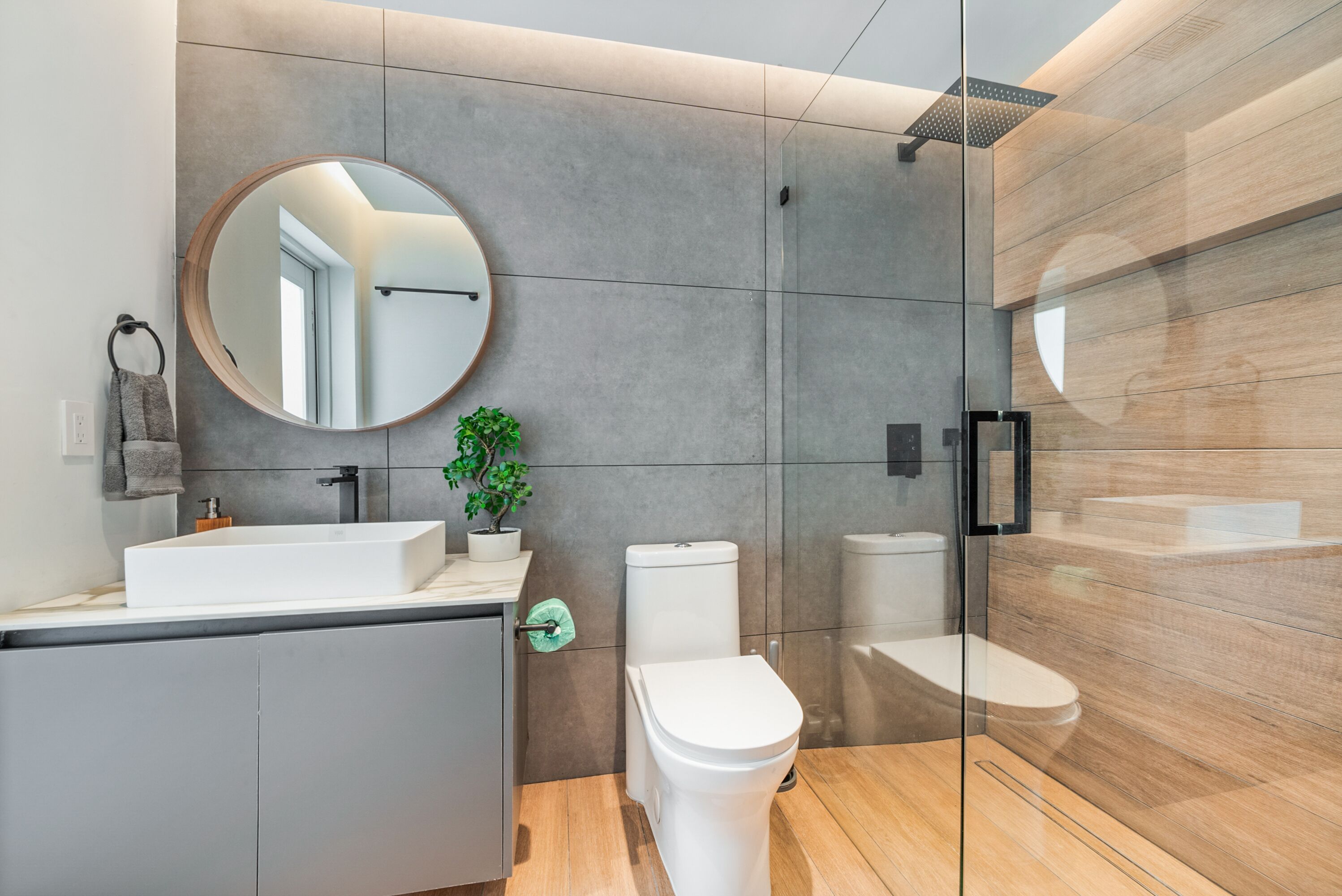 Une salle de bain moderne avec un grand miroir, un lavabo, des toilettes et un espace douche.
