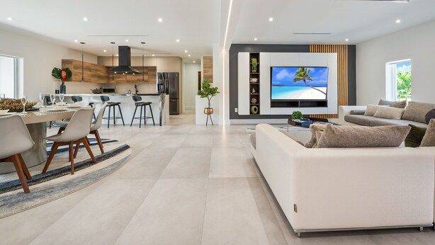 A modern living room with a large flat-screen TV, a sofa, and a dining area with chairs and a table. - Family getaway • Pool • BBQ • Golf • BB Court (Miami)