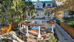 Une maison à deux étages dotée d’un patio couvert, d’un jacuzzi et d’une terrasse en bois.