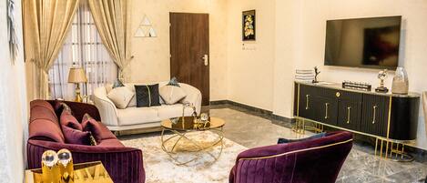 A living room with a sofa, armchairs, a coffee table, a TV, and a cabinet.