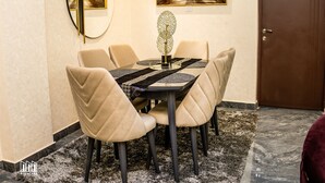 A dining area with a round table, six chairs, a decorative centerpiece, and two framed artworks on the wall. - Gyamfuaa Court Apartment (Kumasi)