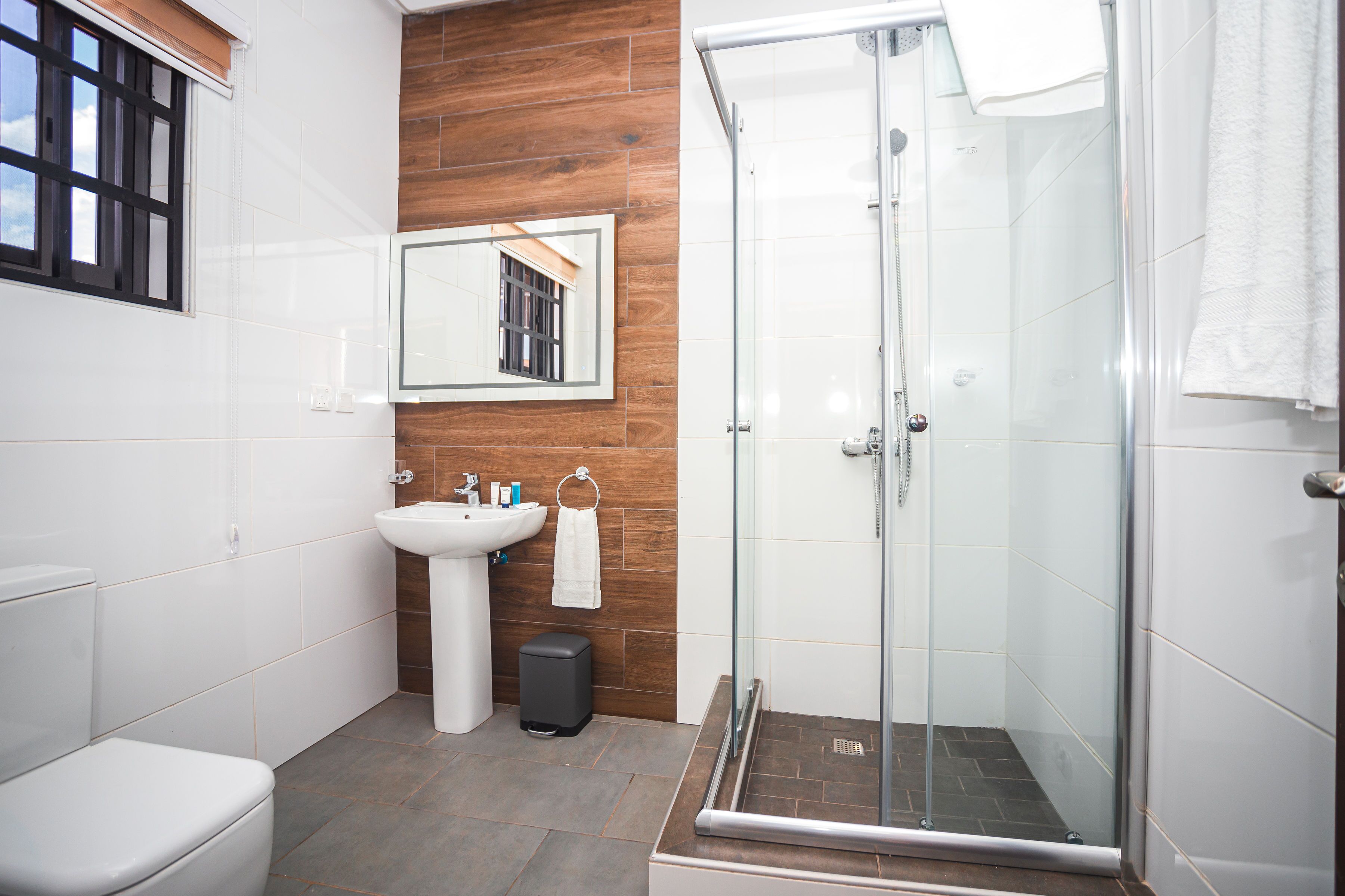 A modern bathroom with a toilet, sink, and glass-enclosed shower.