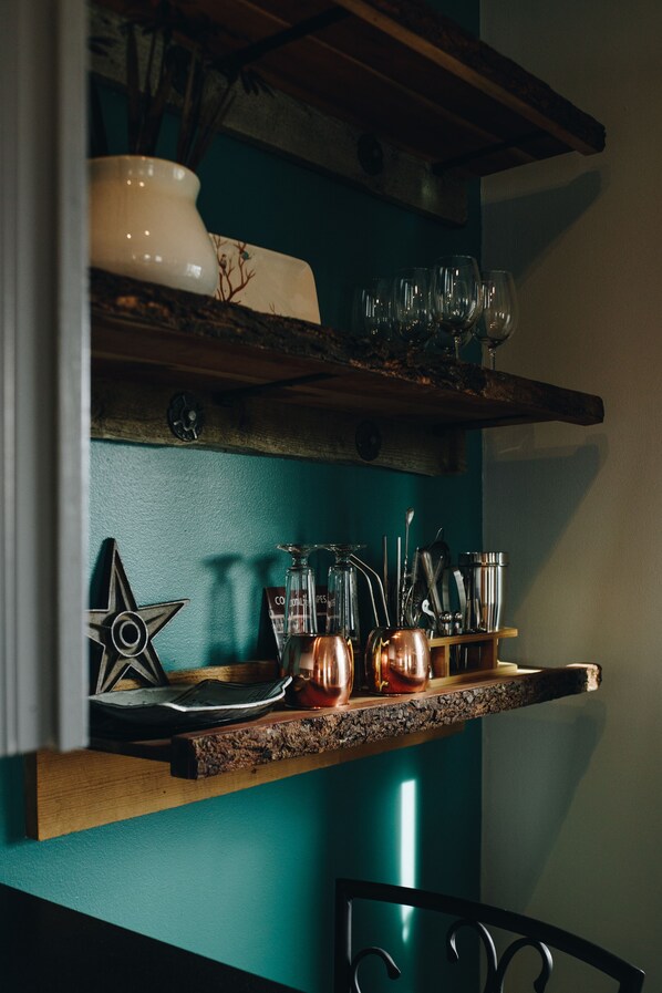 A kitchen shelf with glassware, a star-shaped ornament, and copper pots.