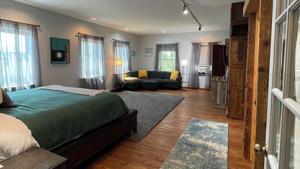 A spacious bedroom with a large bed, a sofa, and a wooden wardrobe. - Connoisseur Hideaway (Bozeman)
