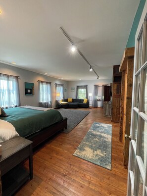 A spacious bedroom with a large bed, a sofa, and a wooden wardrobe.