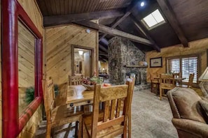Um interior rústico com lareira de pedra, mesa de jantar de madeira e cadeiras.