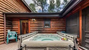 Eine Blockhütte mit Whirlpool auf einer Terrasse.