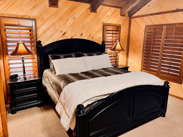 Un dormitorio con paneles de madera, una cama, dos mesitas de noche y dos lámparas.