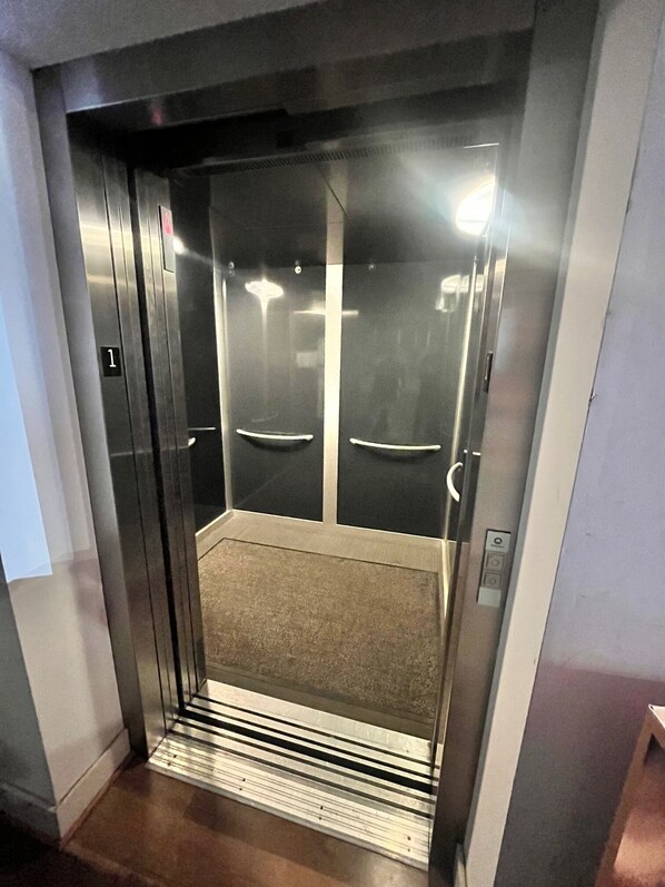 An elevator with a metallic interior, a carpeted floor, and a door marked with the number 1. - 402 Heart of the Arts in Downtown RVA near MCV VCU Convention Center (Richmond)