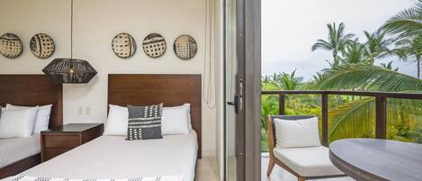 A bedroom with a large bed, a nightstand, a bedside table, and a chair. There is a balcony with a table and chairs, and a view of palm trees.