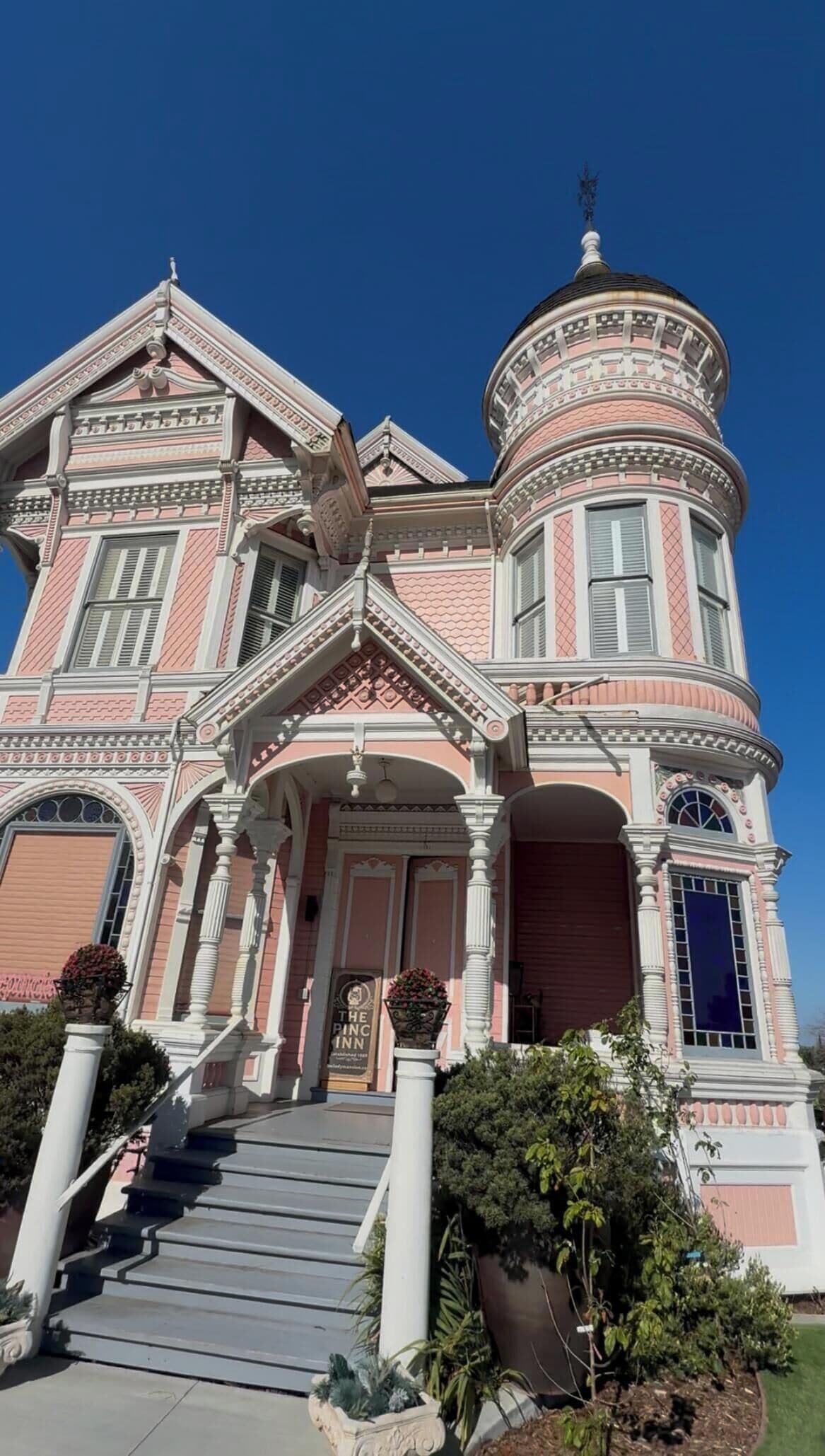 A Victorian-style building with a prominent tower, a grand entrance with steps, and a sign indicating it is a hotel.