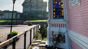 Um edifício rosa com uma grande janela e um varanda decorativa.