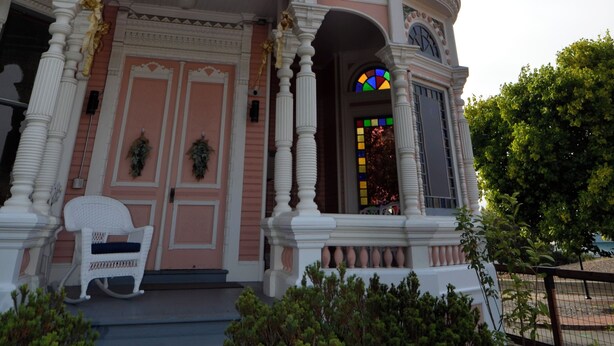 Um edifício histórico com fachada rosa, colunas brancas e uma torre peculiar.