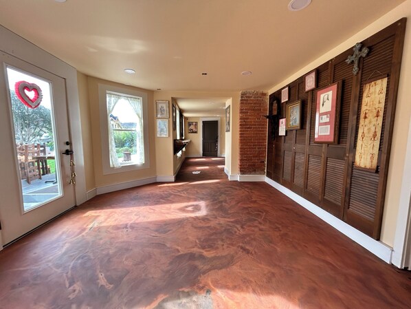A hallway with a polished wooden floor, a door with a heart decoration, and a brick wall with framed pictures. - Pinc Lady Mansion (Eureka)