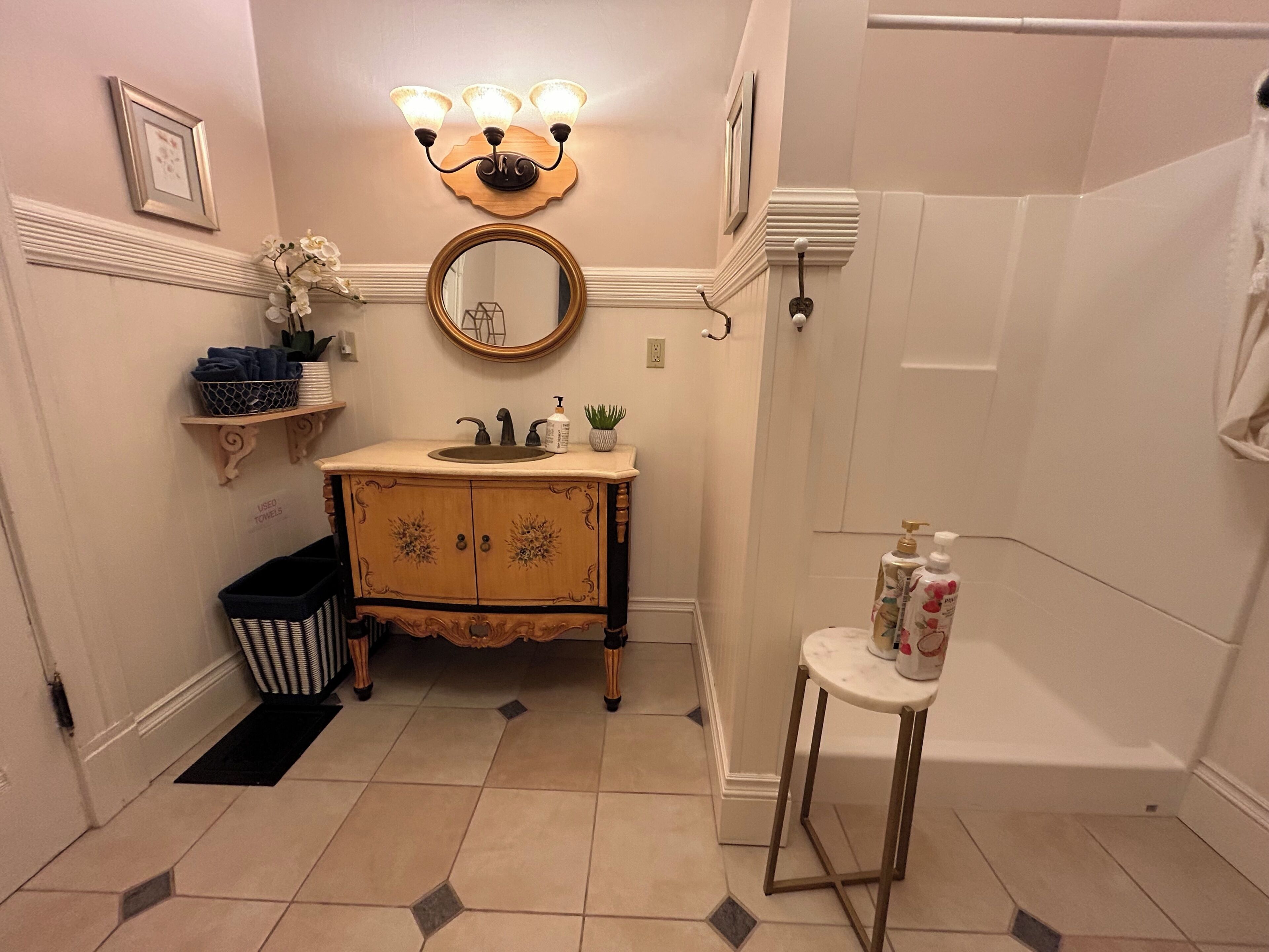 A bathroom with a vanity, sink, mirror, and shower.