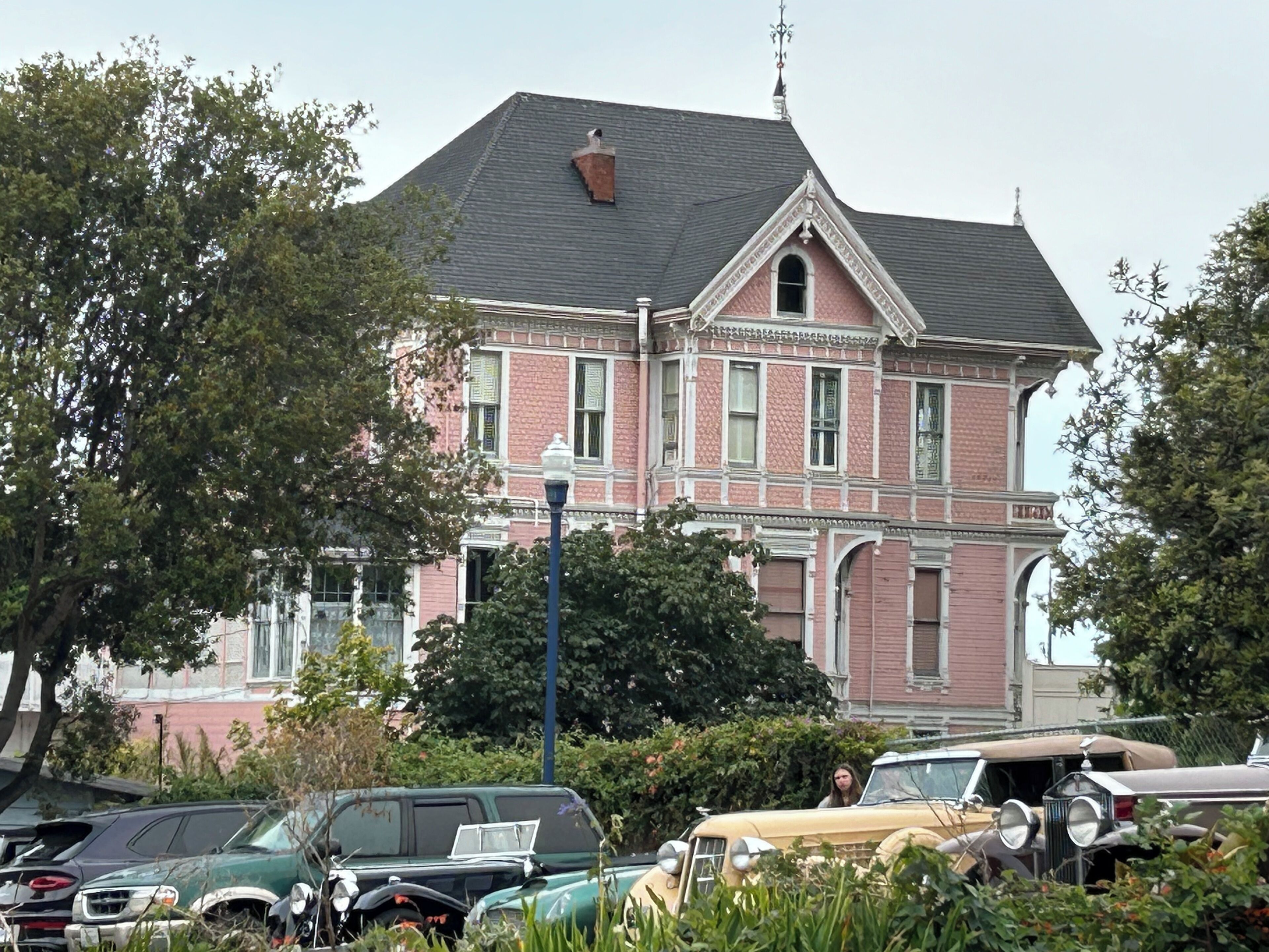 A large, pink brick house with a steep roof and a chimney.