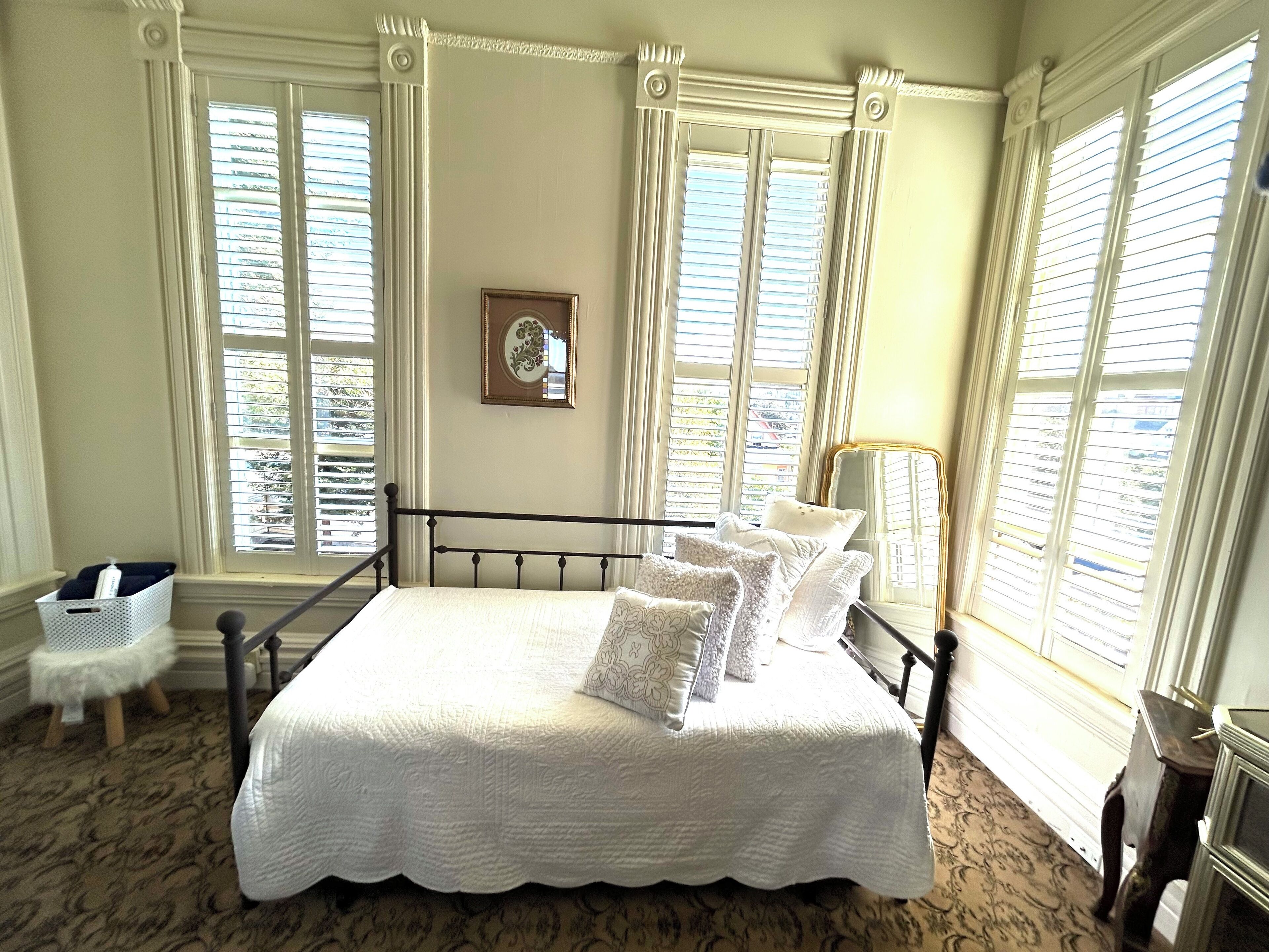 A bedroom with a bed, a bedside table, a chair, and a window with curtains.