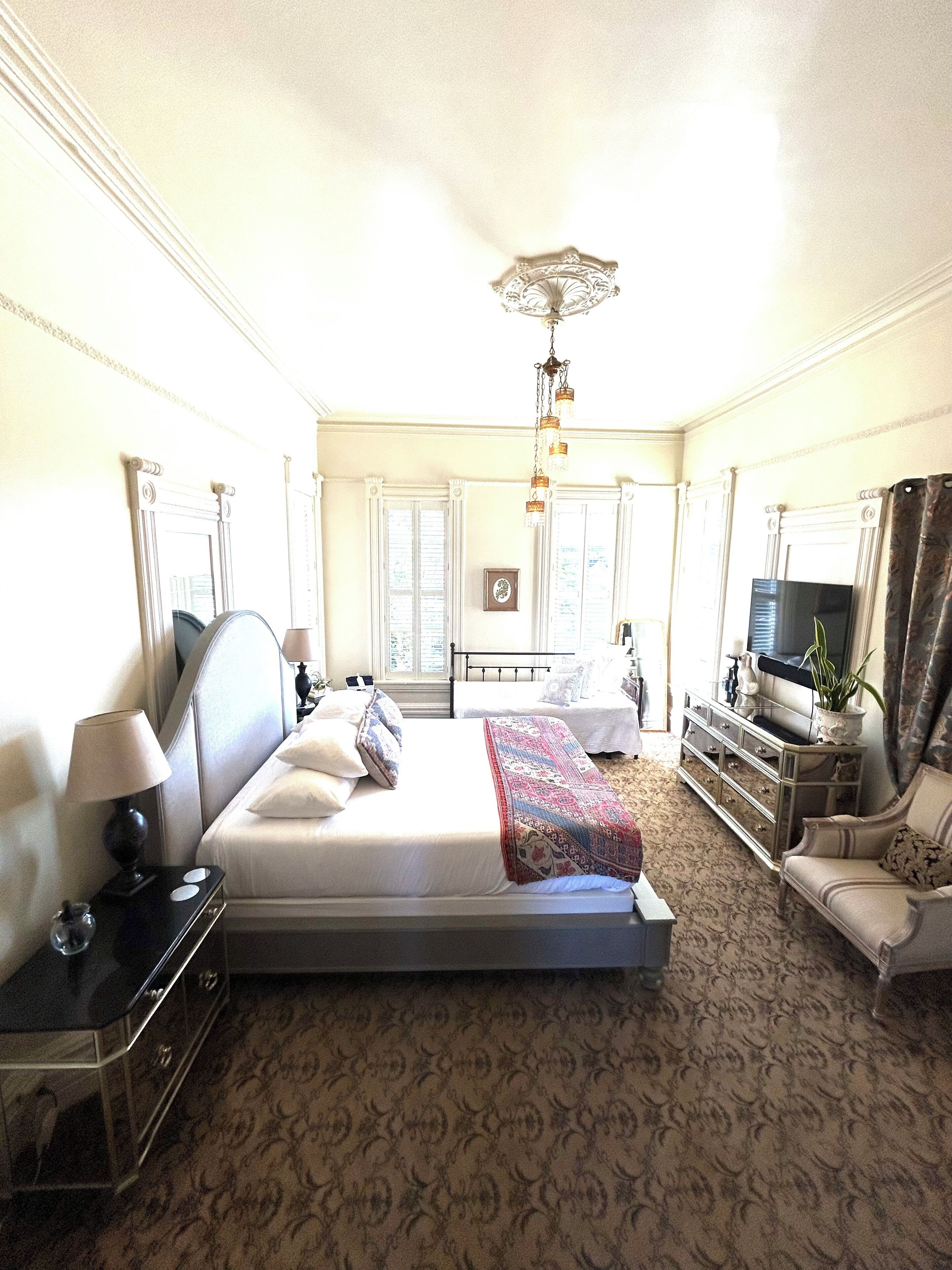 A hotel room with a large bed, a sofa, a TV, and a dresser.